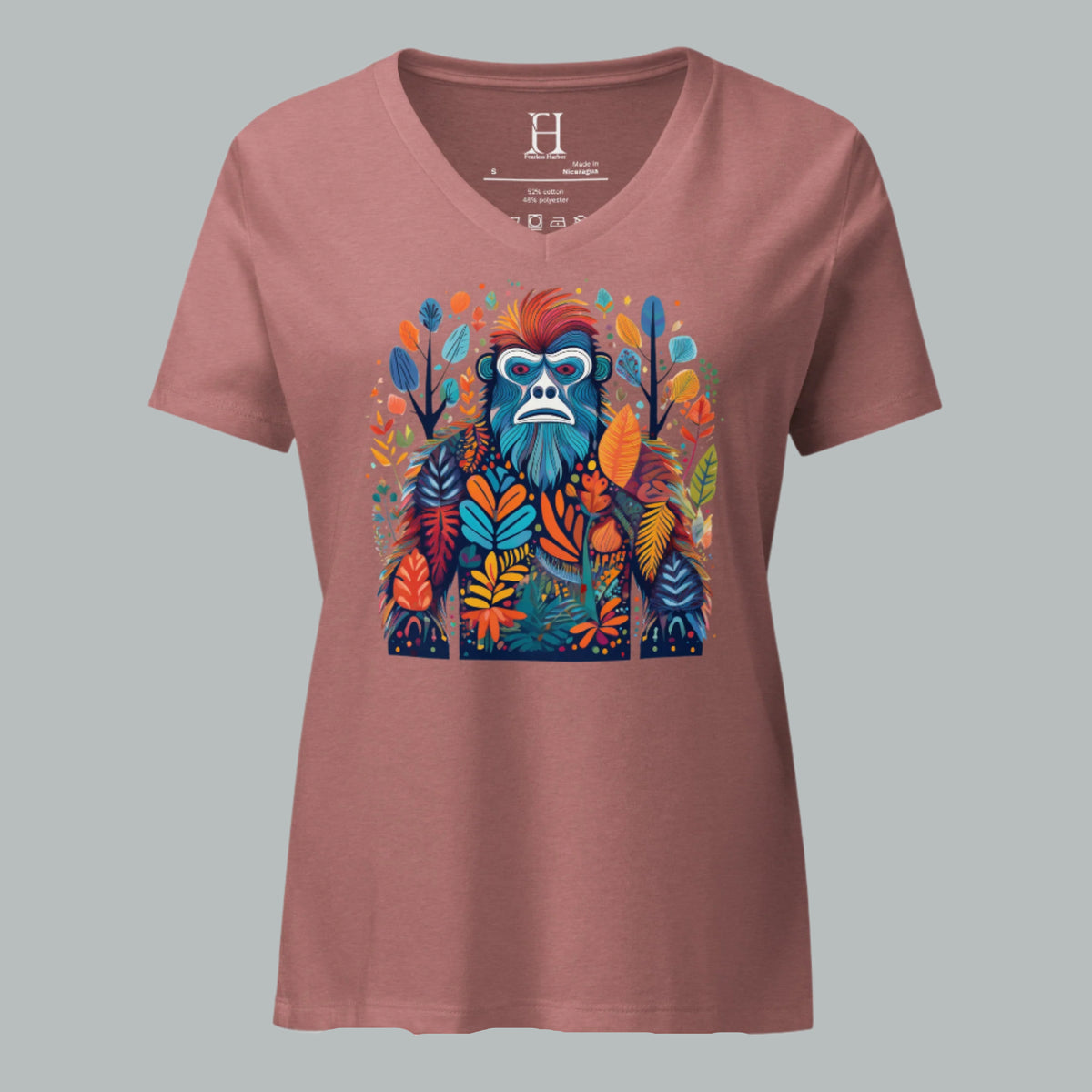 Front of women’s V-neck tee in heather mauve with a multihued camo-style Bigfoot graphic among forest elements.
