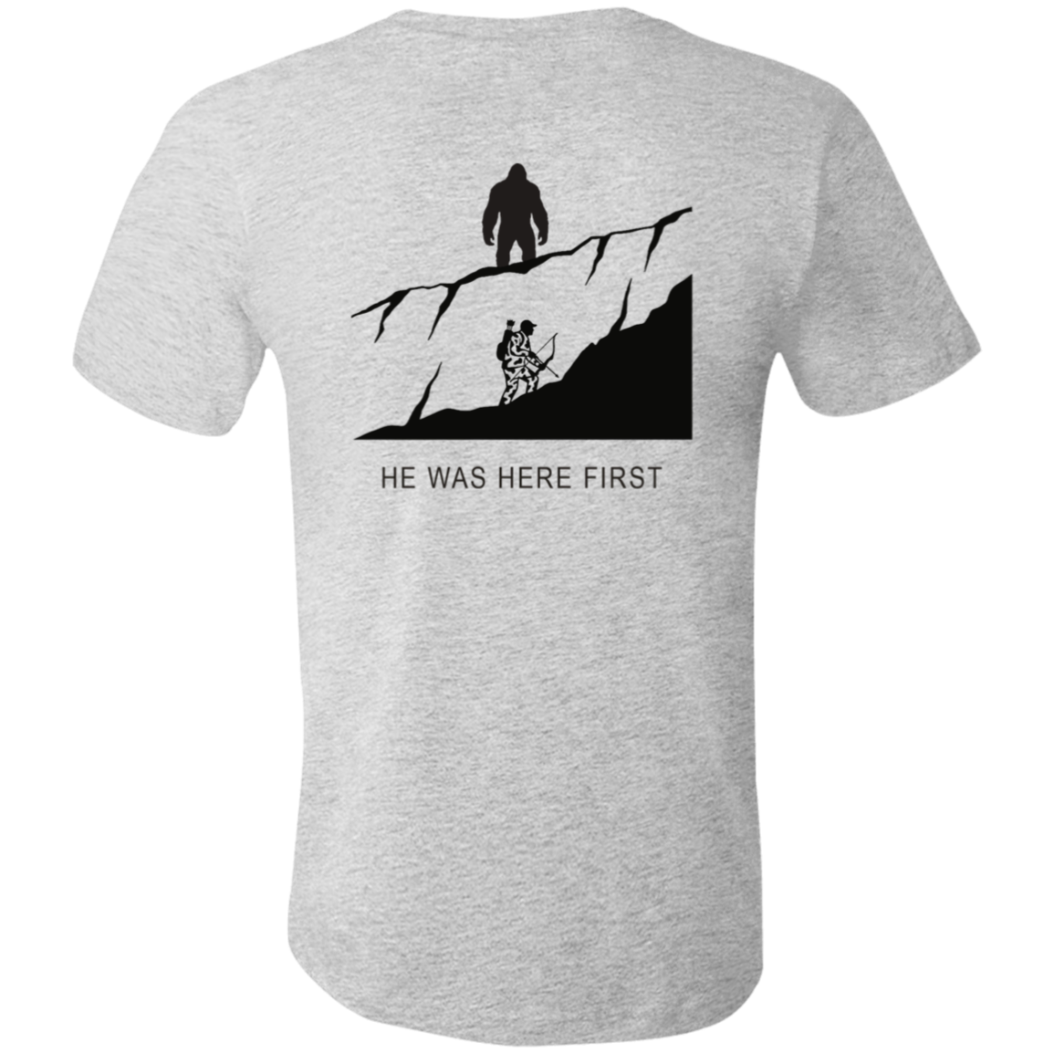 Back view of the Men’s He Was Here First Bigfoot Hunting Tee in Athletic Heather showing a large graphic of Bigfoot standing on a ridge above a climbing bowhunter with He Was Here First text.