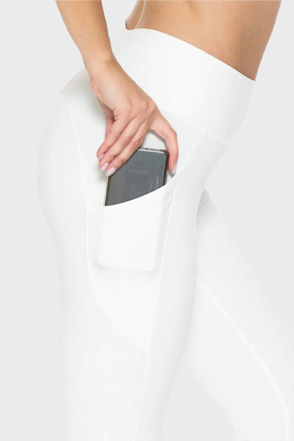 Right Side of Full Size High Waist Leggings with Pockets in White, woman placing phone in pocket blank with no graphics or text. 