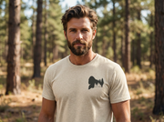 Man wearing a beige t-shirt with a black graphic in a forest setting