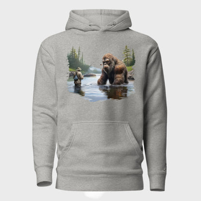 Front of Bigfoot Big Catch Pullover Hoodie in Grey with design of a fisherman and hook caught on Bigfoot sitting in lake.