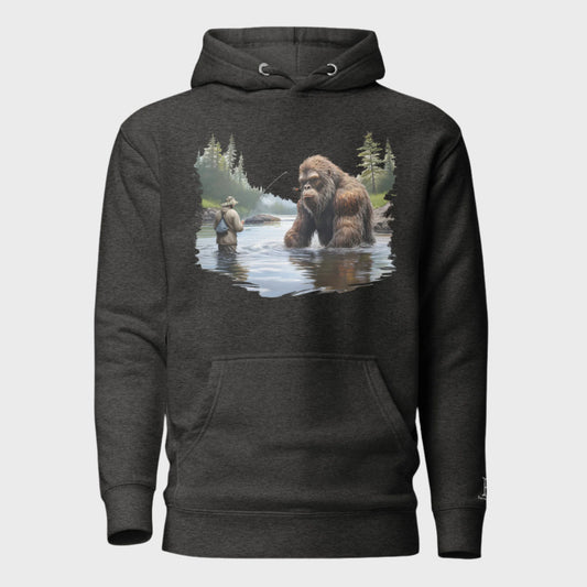 Front of Bigfoot Big Catch Pullover Hoodie in Charcoal with design of a fisherman and hook caught on Bigfoot sitting in lake.