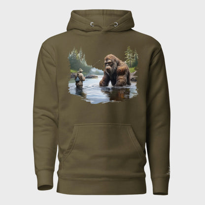 Front of Bigfoot Big Catch Pullover Hoodie in Military Green with design of a fisherman and hook caught on Bigfoot sitting in lake.