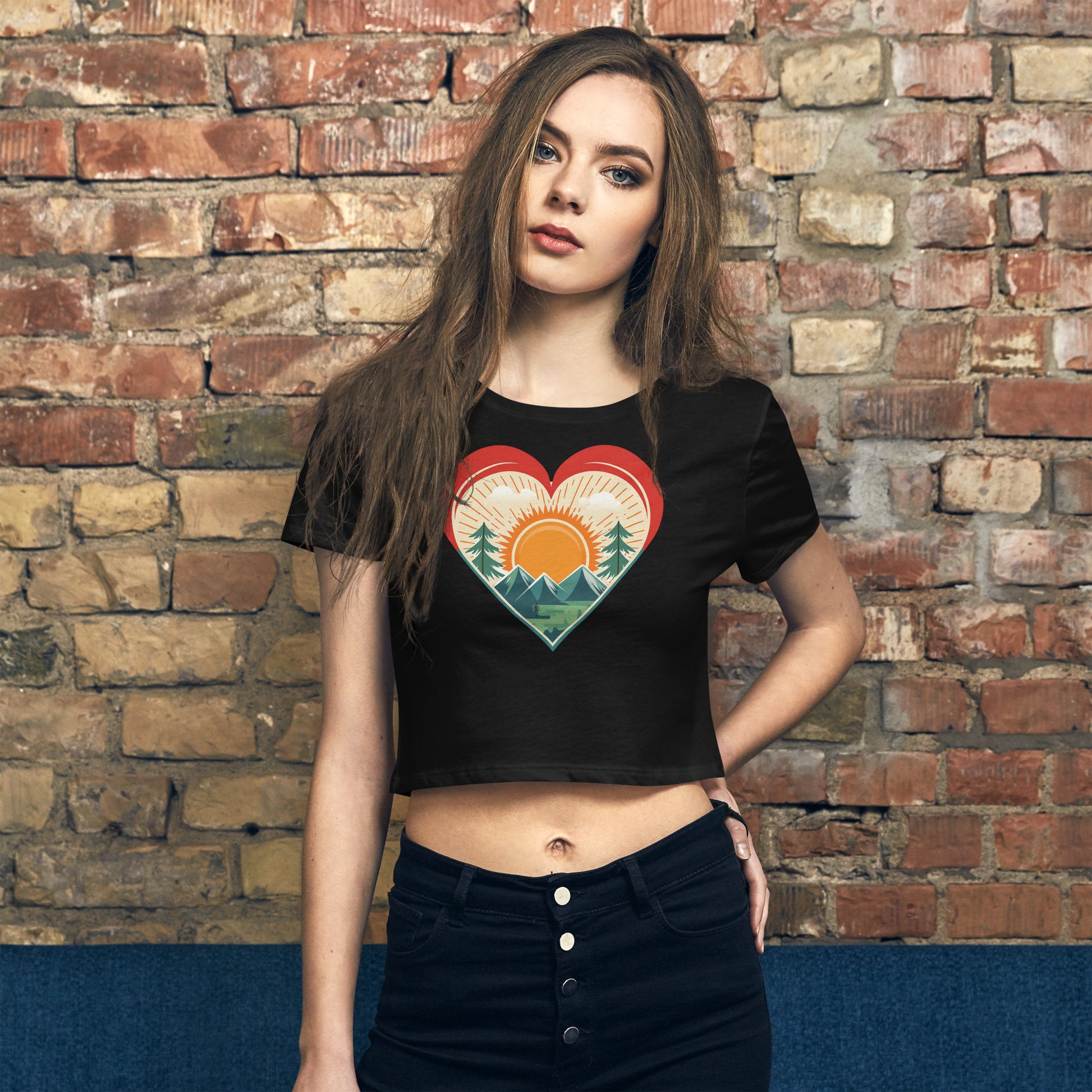 Front of Woman wearing Bold Crop Top Tee in Black, with sun rising over a forest within a heart silhouette design.