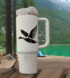 Black flying duck decal applied to a tumbler resting on a picnic table at a campsite—rugged, outdoors-ready hunting aesthetic.