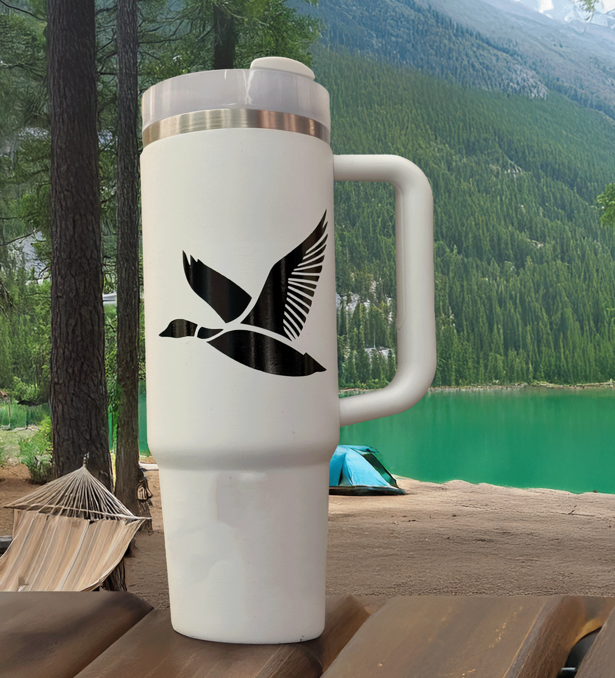 Black flying duck decal applied to a tumbler resting on a picnic table at a campsite—rugged, outdoors-ready hunting aesthetic.