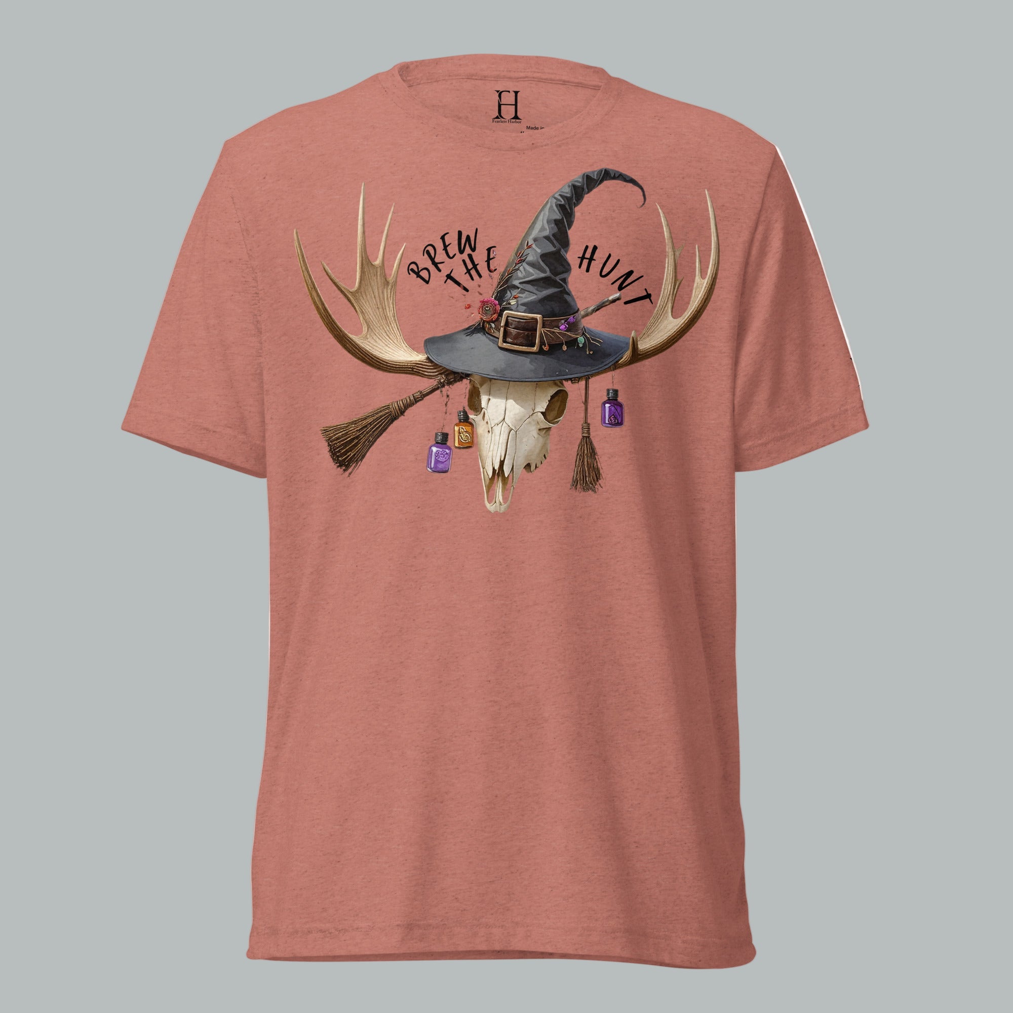 Front view of Fearless Harbor Women's Brew the Hunt Tee in Mauve featuring skull with antlers, witch hat, and broomstick design.