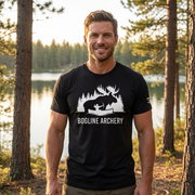 Man outdoors wearing the Men's Bogline Archery Tee in Black front view showing the moose and archer graphic in a field and timber setting
