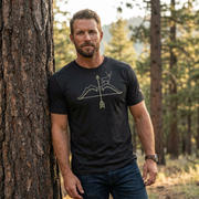 Man outdoors wearing the Men's High Desert Mule Deer Bowline Tee in Black Heather front view showing the mule deer ridge and arrow graphic