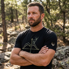 Man outdoors wearing the Men's High Desert Mule Deer Bowline Tee in Black Heather side view showing the High Desert Rack mule deer emblem