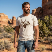 Man outdoors wearing the Men's Mesa Mule Deer Tee in Heather Dust front view showing the mule deer and mesa country artwork