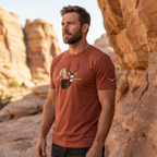Man outdoors wearing the Men's Rimrock Mule Deer Tee in Clay Triblend with the High Desert Rack mule deer emblem on the left front sleeve