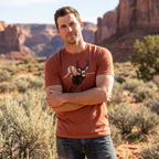 Man outdoors wearing the Men's Rimrock Mule Deer Tee in Clay Triblend front view showing the mule deer buck and rimrock artwork